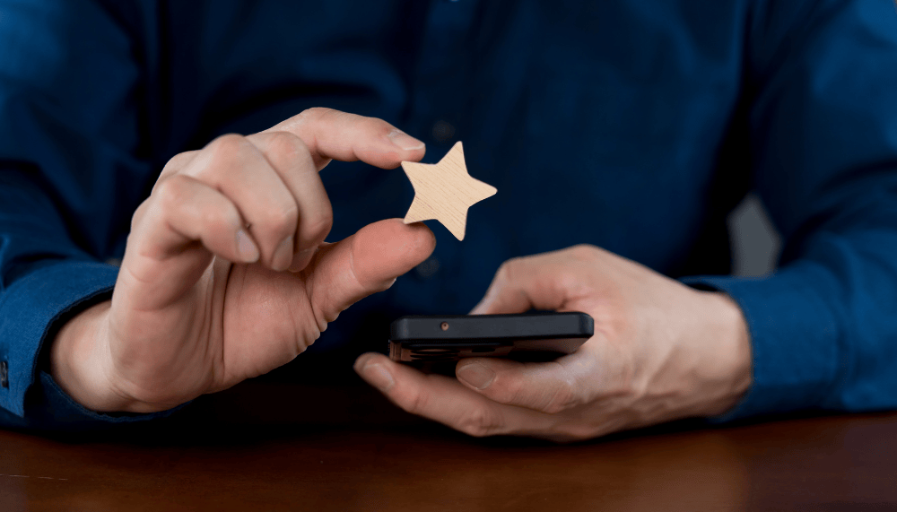 Homme qui tient une etoile avis client au dessus d un smartphone